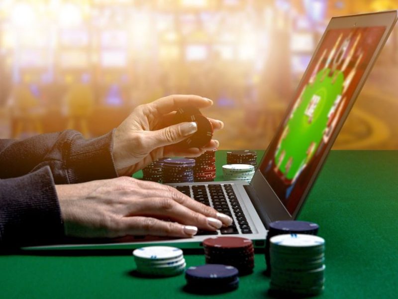 Woman hands with Gambling Chips using laptop for playing online casino. Concept virtual leisure activity.